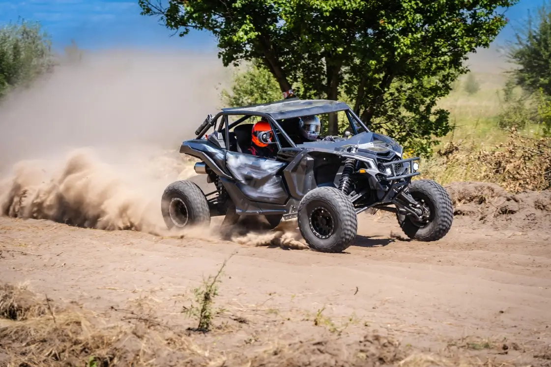 Two-person gray UTV drifting on sandy trail