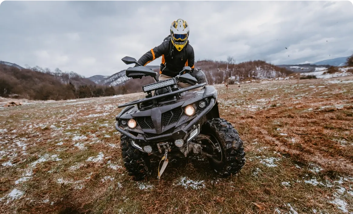Person riding ATV on snowy field.