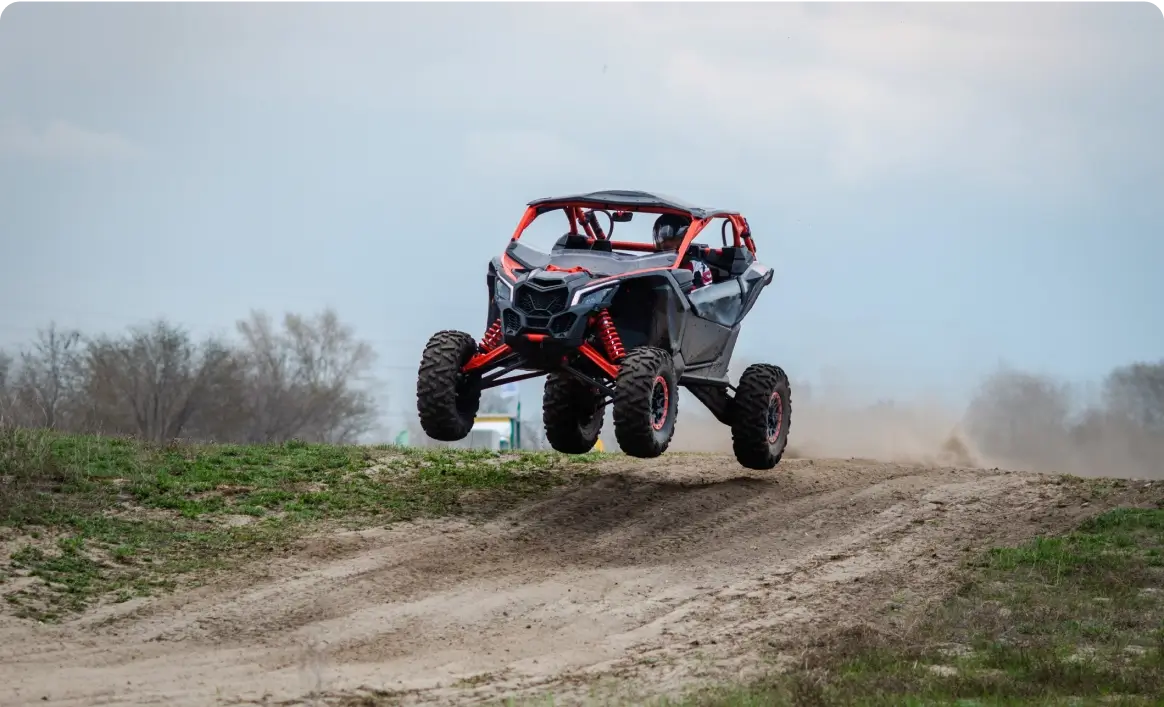 Off-road vehicle jumping on dirt track.
