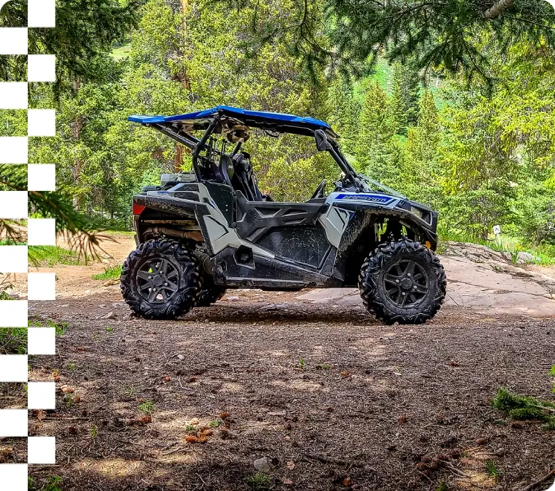 Off-road vehicle parked in forest clearing.