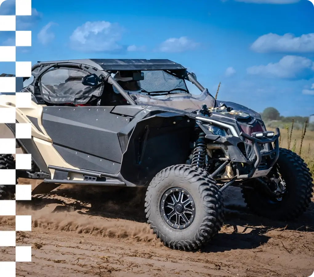 Off-road vehicle driving on sandy terrain.