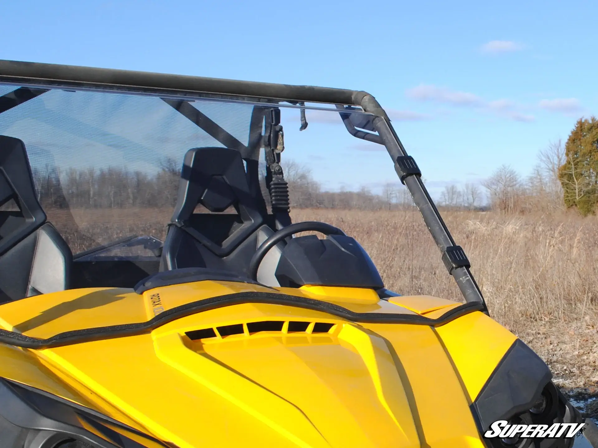 Yellow off-road vehicle parked in an open field under a clear sky.