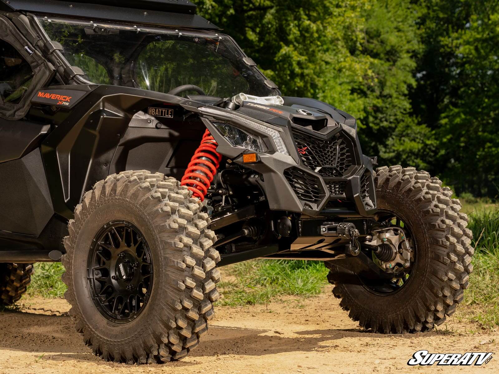A rugged off-road vehicle with large tires and red suspension on a dirt path.