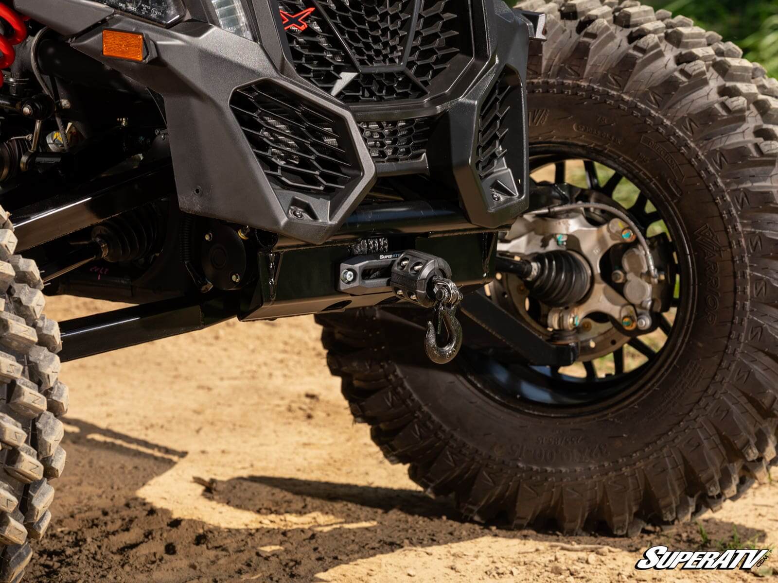 Close-up of an off-road vehicle's suspension and tire on sandy terrain.