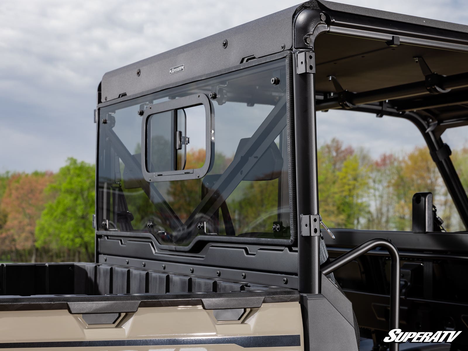 Close-up of a rugged vehicle's rear window and bed under a cloudy sky.