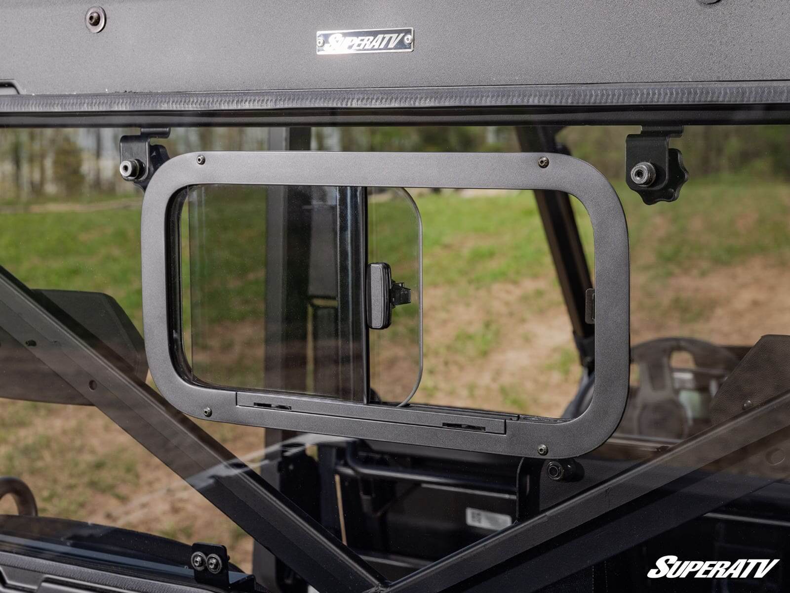 Open window frame on a vehicle door showing the outside landscape.