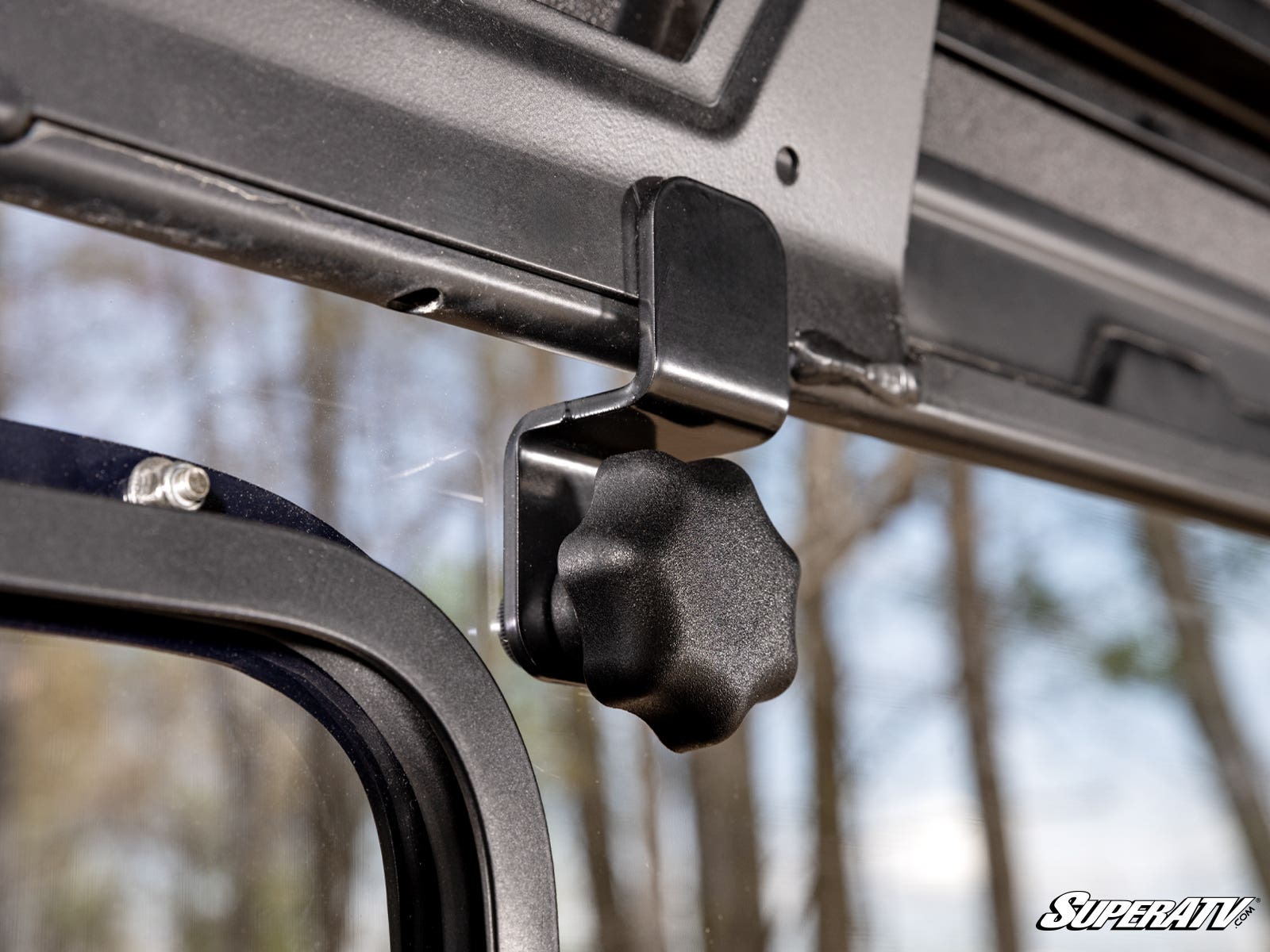 Close-up of a black knob attached to a metal frame outdoors.
