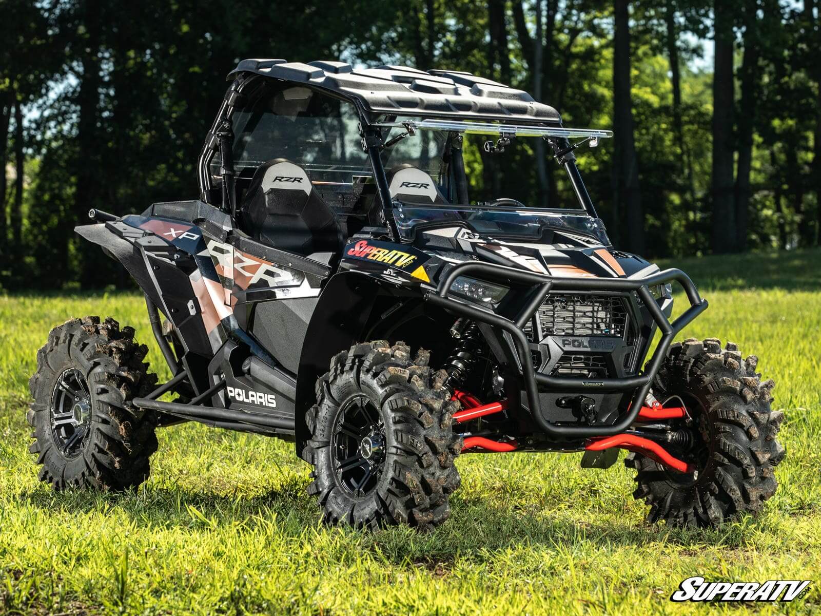 A rugged black off-road vehicle parked on grass with large tires and a roll cage.