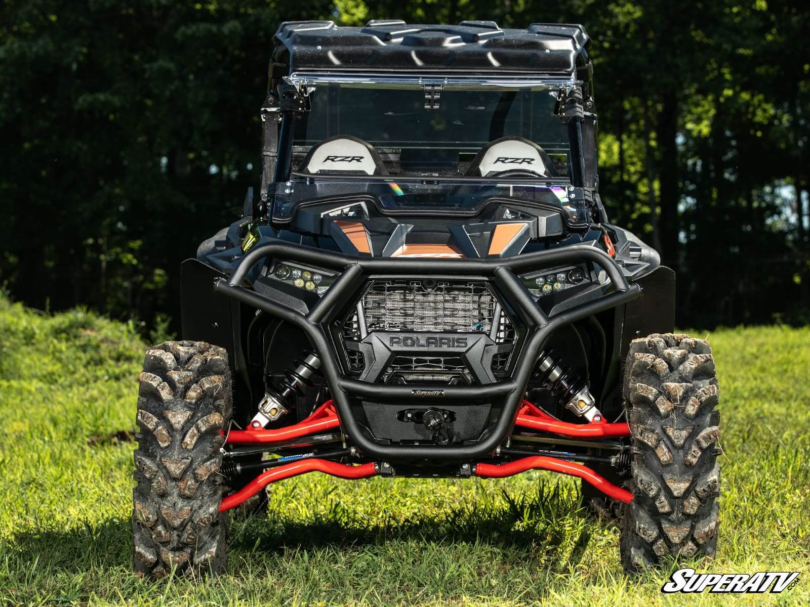 Off-road vehicle parked on grass with rugged tires and roll cage.