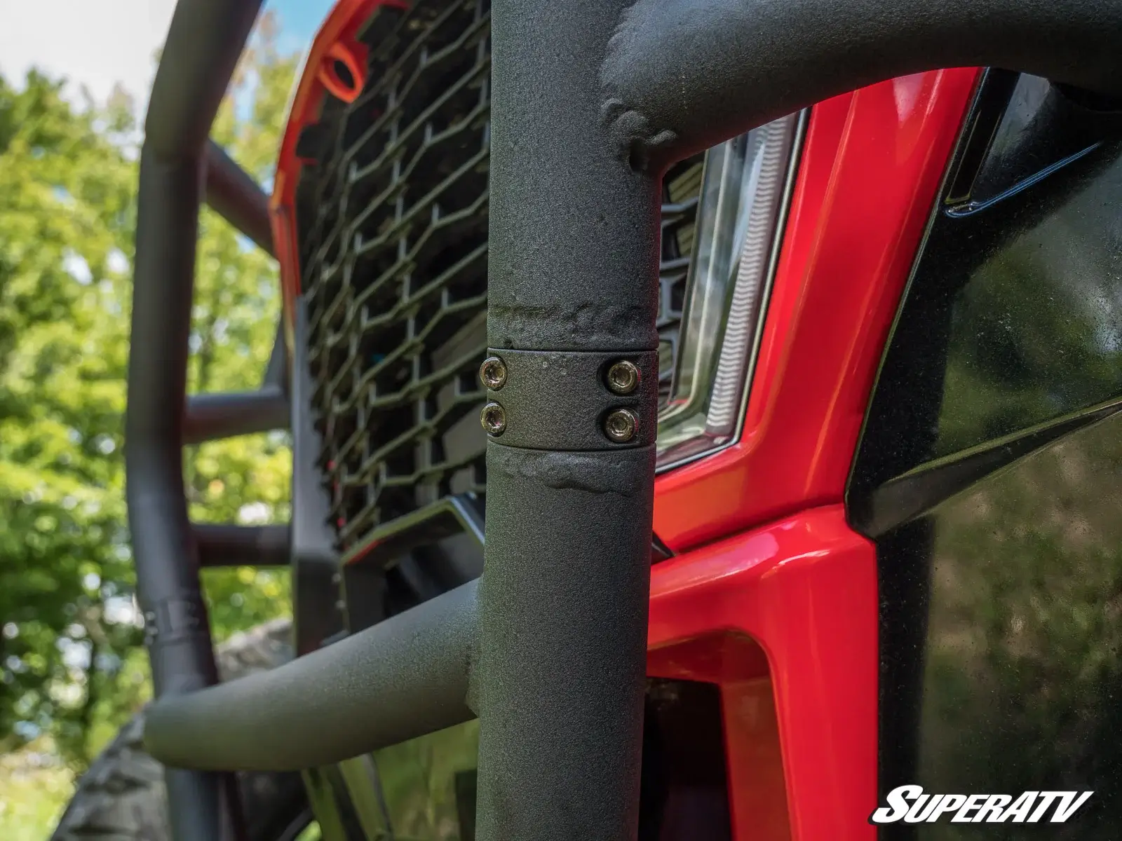 Close-up of a rugged black grille guard on a red off-road vehicle.