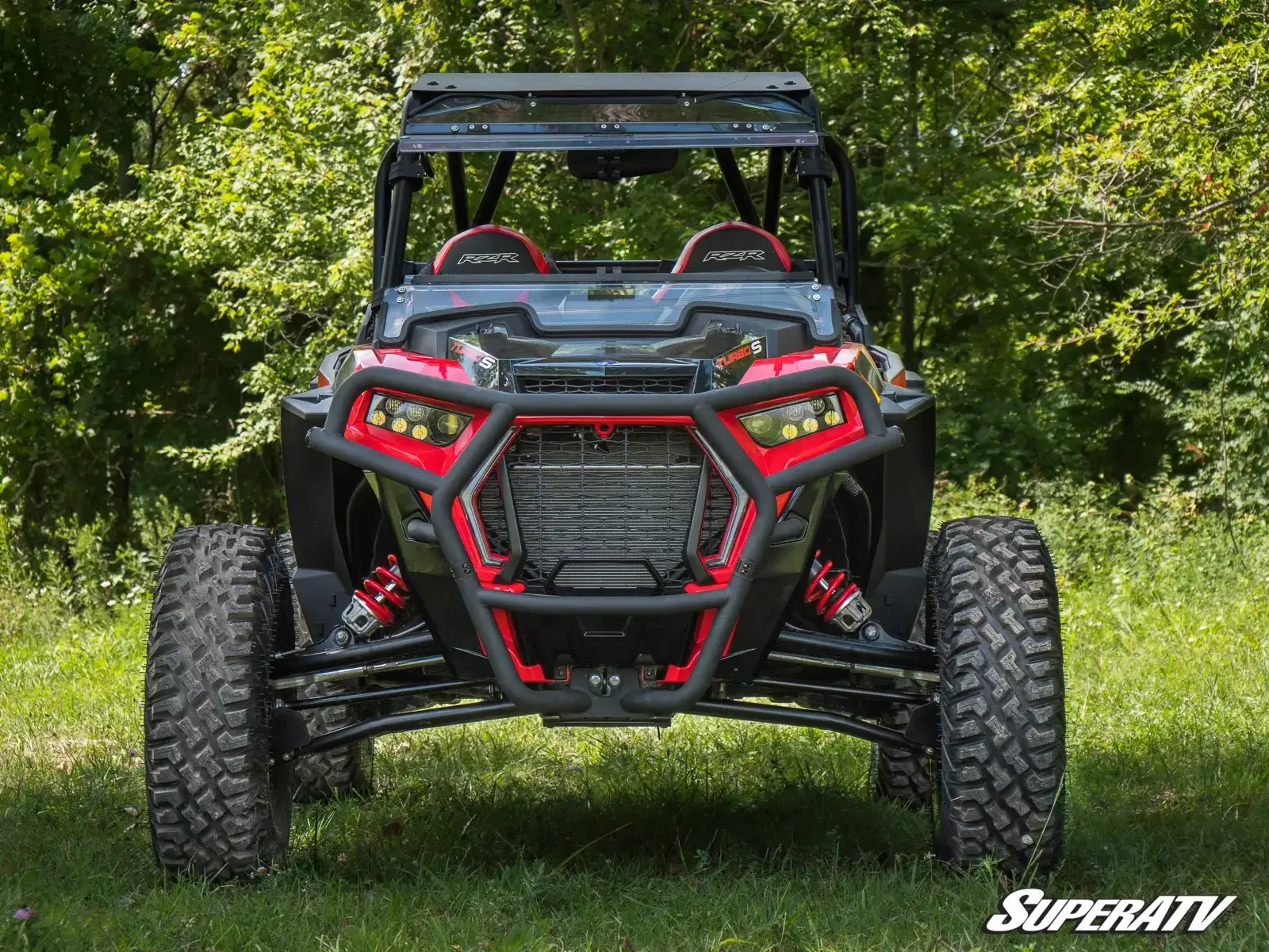 Off-road vehicle parked on grass with trees in the background.