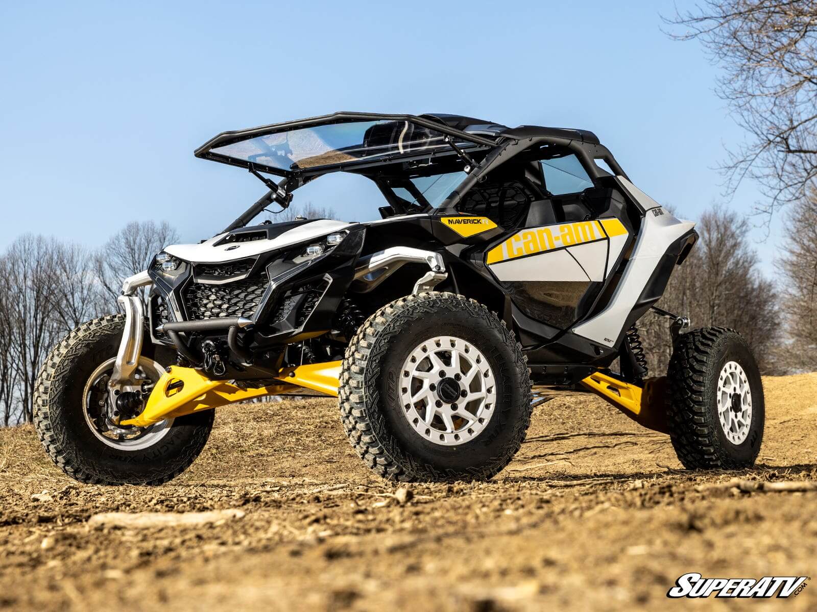 A yellow and black off-road buggy on dirt terrain under a clear blue sky.