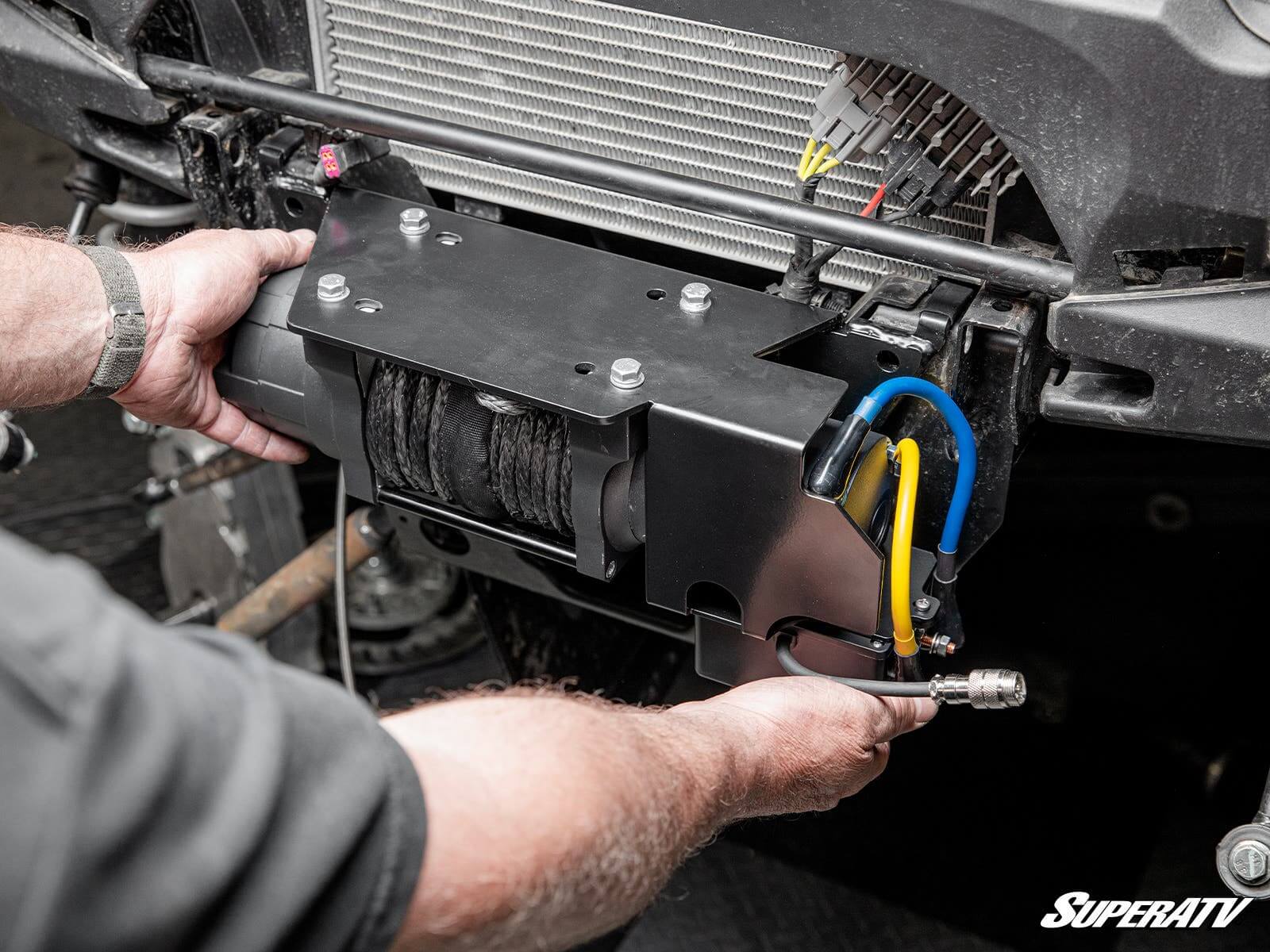 Mechanic installing a car intercooler with wiring connections.