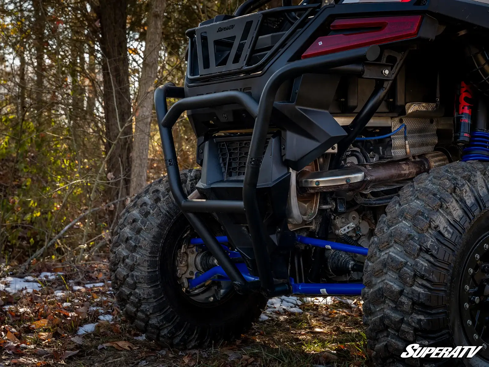 Close-up of a rugged off-road vehicle tire and suspension in a forest.
